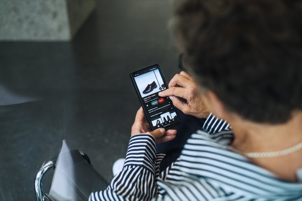 &Auml;ltere Frau tippt auf ihrem Smartphone auf die Produktseite eines Online-Shops